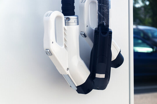 Electric vehicle charging plugs on station wall at public parking lot at sunny summer daytime