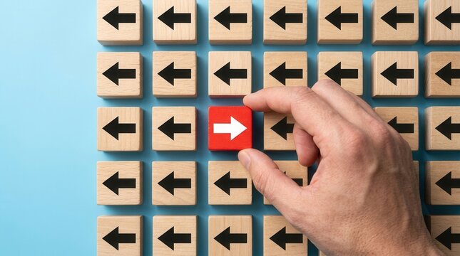 A hand placing a red arrow block in the opposite direction among black arrows for leadership and innovation.