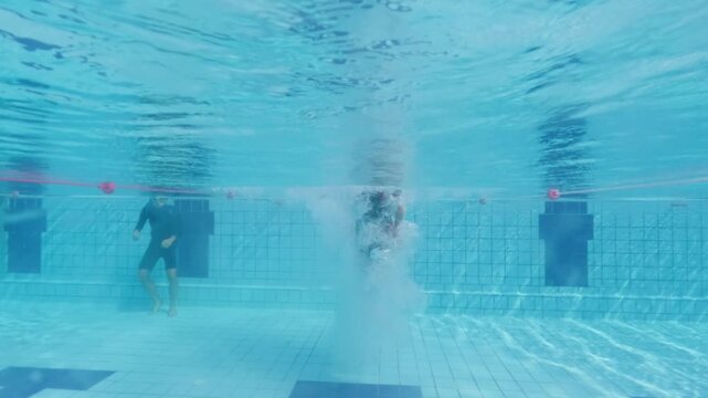 Athletic young boy diving to outdoor swimming pool from starting block.