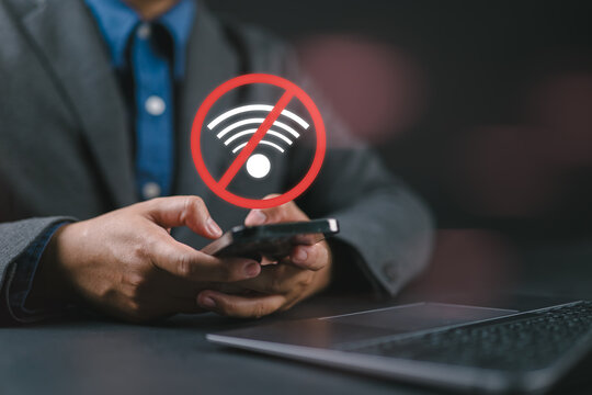 Man holding a smartphone with a red no wifi icon. This offline digital technology concept shows internet network connection error, communication problem, and disconnected signal.
