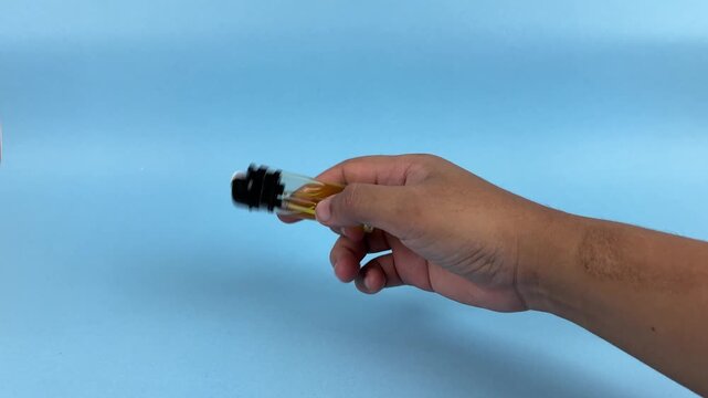 Hand Holding Lighter with Flame on Blue Background Close Up