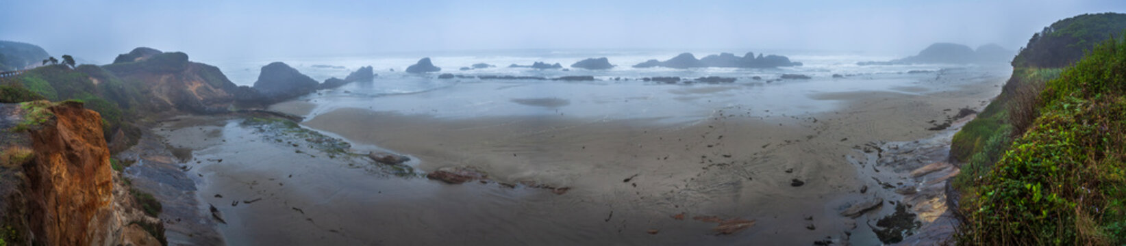 Beautiful wide panoramic view of a wild ocean sandy coast with misty mountains, sea stacks and seagulls