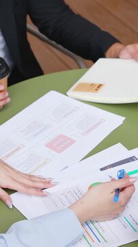 Overhead View of Colleagues Discussing Financial Charts and Documents During Meeting
