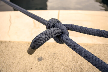 Fototapeta premium Sheet bend knot tied in heavy black braided mooring line at the port of Rijeka, Croatia. Nautical rope knot detail.