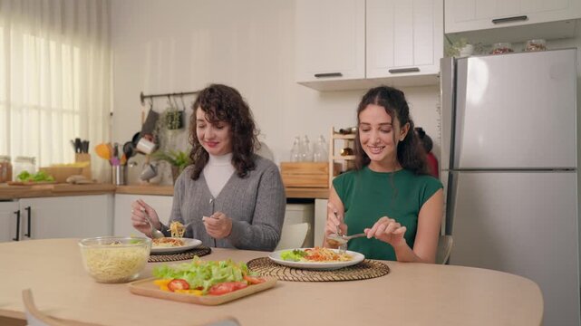 Senior Latino mother and young adult daughter enjoying a homemade meal.