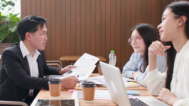 Asian Business Team Discussing Reports and Celebrating Success in Meeting Room