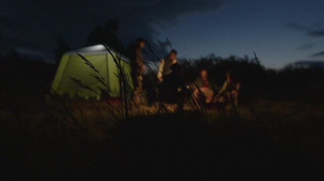 Group of men camping in the wild and gather near the bonfire and talk with each other. Fishermen camping and talk stories at night