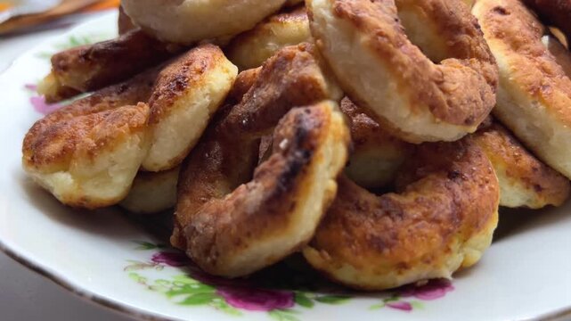 Golden brown fried dough rings piled on a white plate, crispy snack, indulgent treat, comfort food.