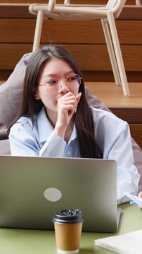 Thoughtful Asian Businesswoman with Laptop Working in Modern Coworking Space
