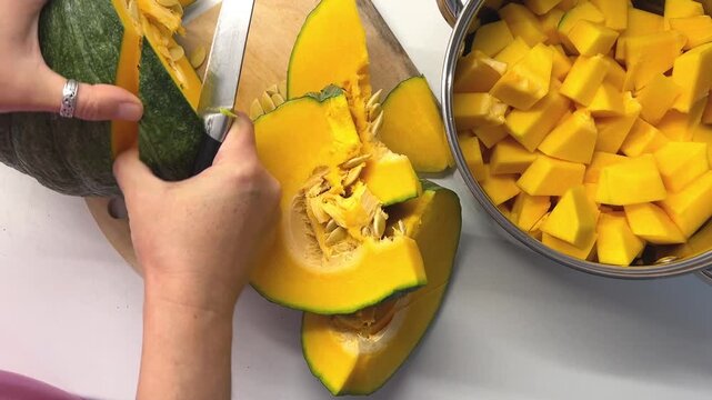 Hand scooping pumpkin pulp from a halved ripe pumpkin, autumn vegetable, fresh produce, seasonal treat.