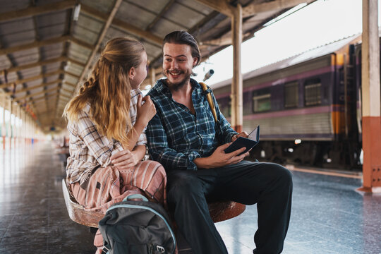 Couple planning trip holding passport at train station