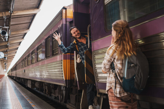 Happy travelers waving goodbye on train platform