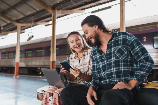 Happy young couple traveling together at train station