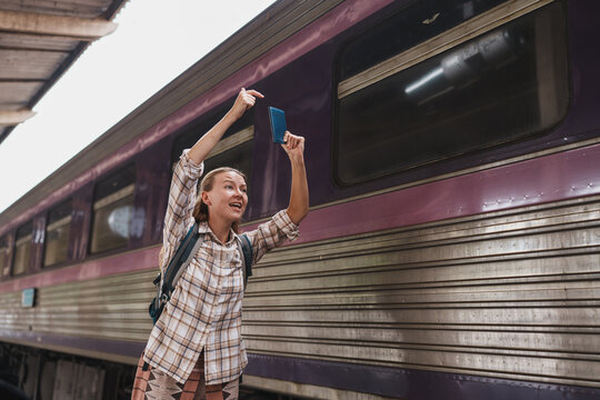 Woman holding passport and pointing at train window