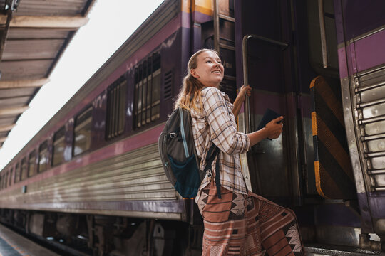Happy young woman boarding train at station