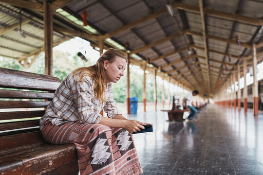 Traveler woman sitting waiting on train station platform