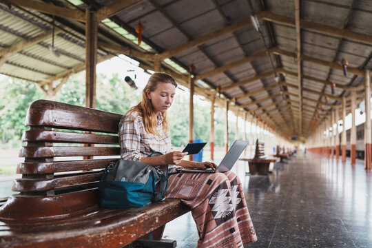 Woman working on laptop while waiting at train station