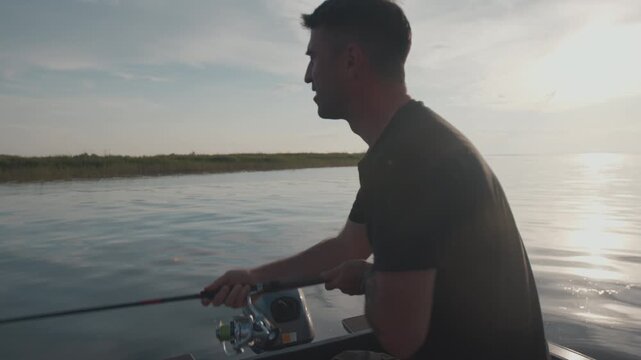 Amateur angler fishing on the river from a boat at sunset