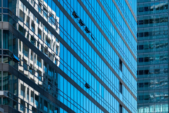 Blue glass facades with repeating windows and layered reflections create a dense geometric pattern of contemporary urban architecture.
