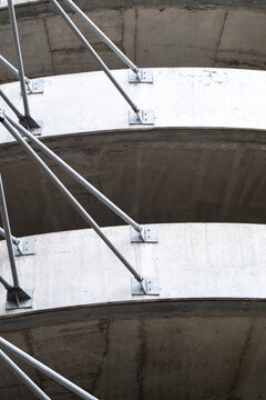 Curved concrete levels and metal railings create repeating lines in a multilevel structure, forming an abstract study of urban architecture and raw materials.