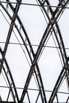 Black steel framework forms an abstract lattice of intersecting lines against a bright background, emphasizing structure, geometry and contemporary architectural detail.