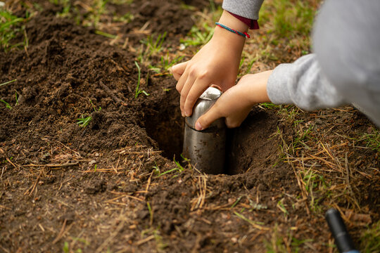 Bury a time capsule with a message for future generations with your child.A message for posterity in the land.The child's hands take out a metal jar from the ground.