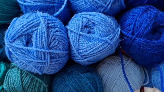 A pile of colorful blue yarn balls for knitting. Traditional craft materials, soft wool textile, handmade hobby.