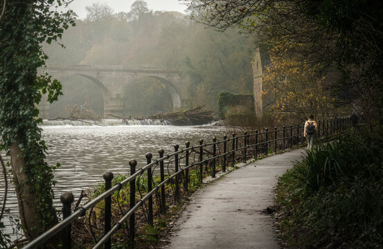 Woman walks pathway beside River Wear in Durham