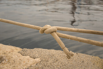 Sheet bend knot tied in light braided mooring rope above water in the port of Rijeka, Croatia. Seamanship knot detail. © YuliiaKettu