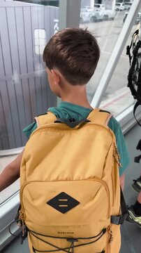 Two Boys with Backpacks Walking Through an Airport Jet Bridge