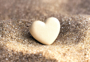 Fototapeta premium Small heartshaped object delicately placed on fine sand background showing simplicity and love concept