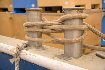 Fototapeta premium Mooring rope wrapped around a steel double bitt deck cleat on a ship in Rijeka harbor, Croatia. Vessel deck hardware detail.