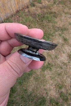 Small silver vase from Vietnam, last century, held in hand against grassy background