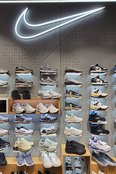 Penang, Malaysia - Sep 06, 2026: Modern footwear display wall in a Nike retail store featuring an illuminated swoosh logo above rows of athletic sneakers and lifestyle shoes inside a shopping mall.