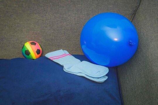 Colorful ball, blue balloon, and socks on a couch in a living room during the daytime