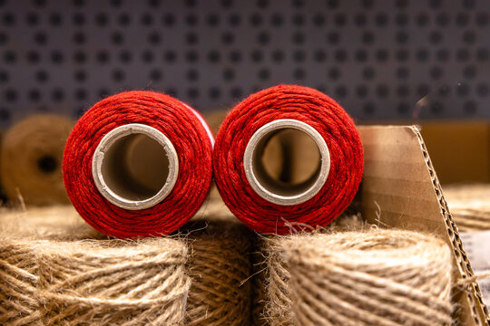 Red and brown spool of natural jute twine displayed on a store shelf, with the rustic fiber cord partially unwound