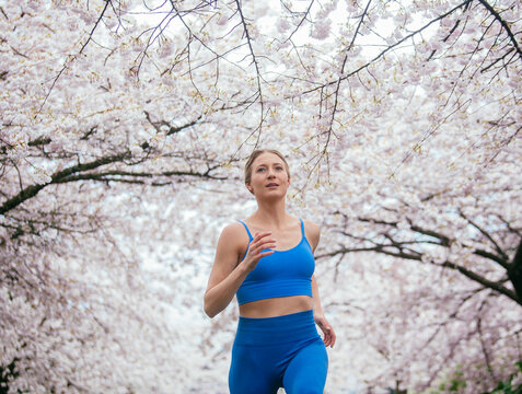 White woman running outdoors in blooming cherry blossoms in USA spring