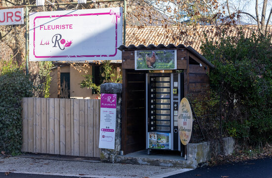 Entrevaux, France - December 26, 2025: A fleuriste sign and a wooden egg vending machine stand beside a road.