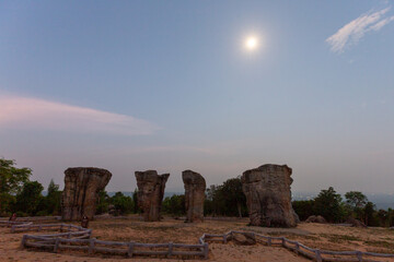 Mor Hin Khao rock formations standing on a hilltop under a bright moonlit twilight sky. © wannasak