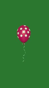 Pink polka dot balloon floating in the air on green screen vertical video.