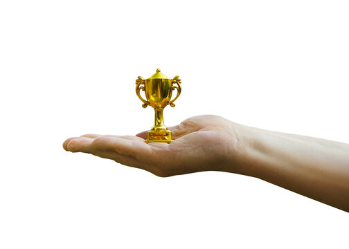 Hand holds and raised small cup trophy, holding cup against isolated on free png backgrund. Consolation prize award and victory concept.