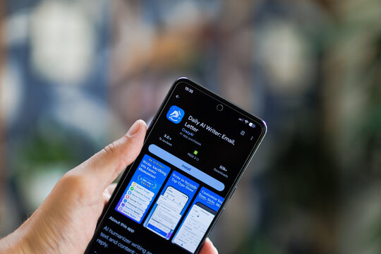 Hand holds phone displaying app store screen for Daily AI Writer Email Letter