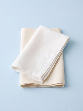 Two folded linen napkins on a light blue background