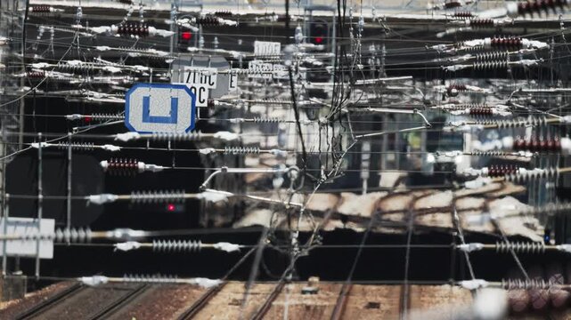 Subway train passing through complex railway catenary wires