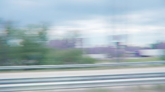 A blurry landscape shot capturing trees and buildings with a motion blur effect, suggesting movement or speed