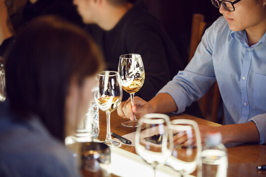Faceless Sommelier Expertly Swirling White Wine at Indoor Degustation Event
