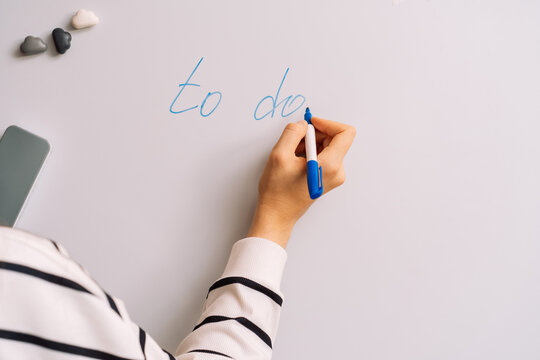 Hand writing to do on a whiteboard in blue beside three small magnets.