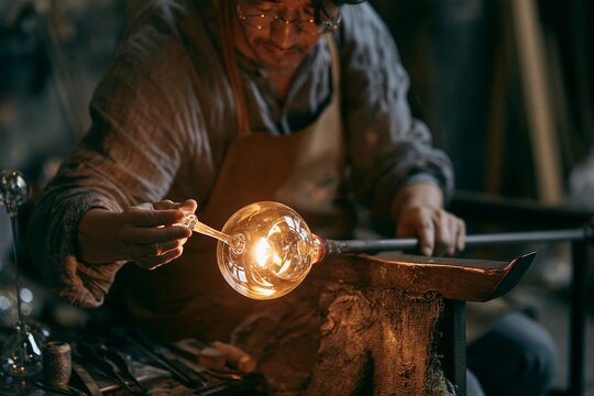 Glassblower shaping a glowing glass wind chime