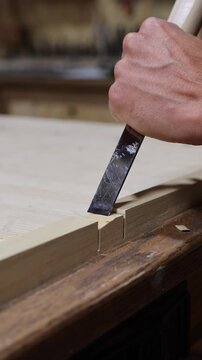 Carpenter crafting wood joint using a chisel