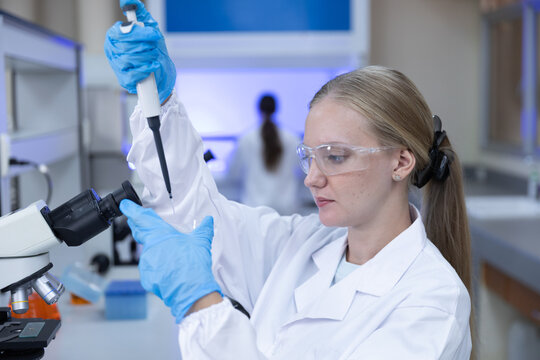 Biotechnology research concept. women scientist using micropipette to prepare sample beside microscope in laboratory. scientist, research, laboratory, pipette, science.